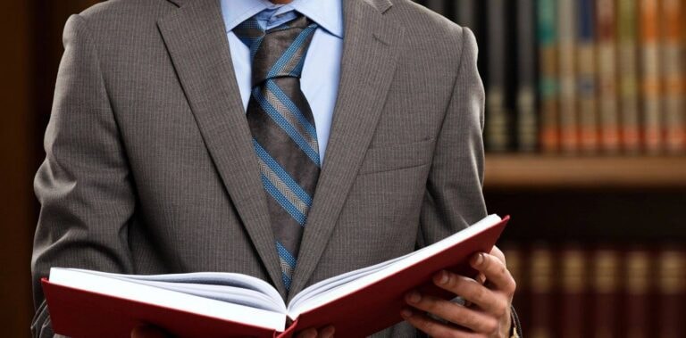 Attorney in suit holding open law book in library